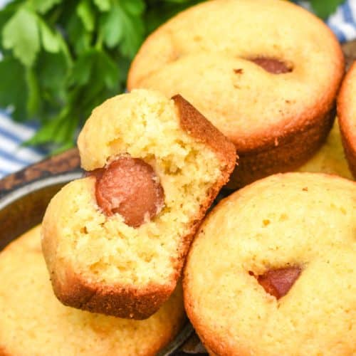 corn dog muffins stacked together on the edge of a metal muffin tin