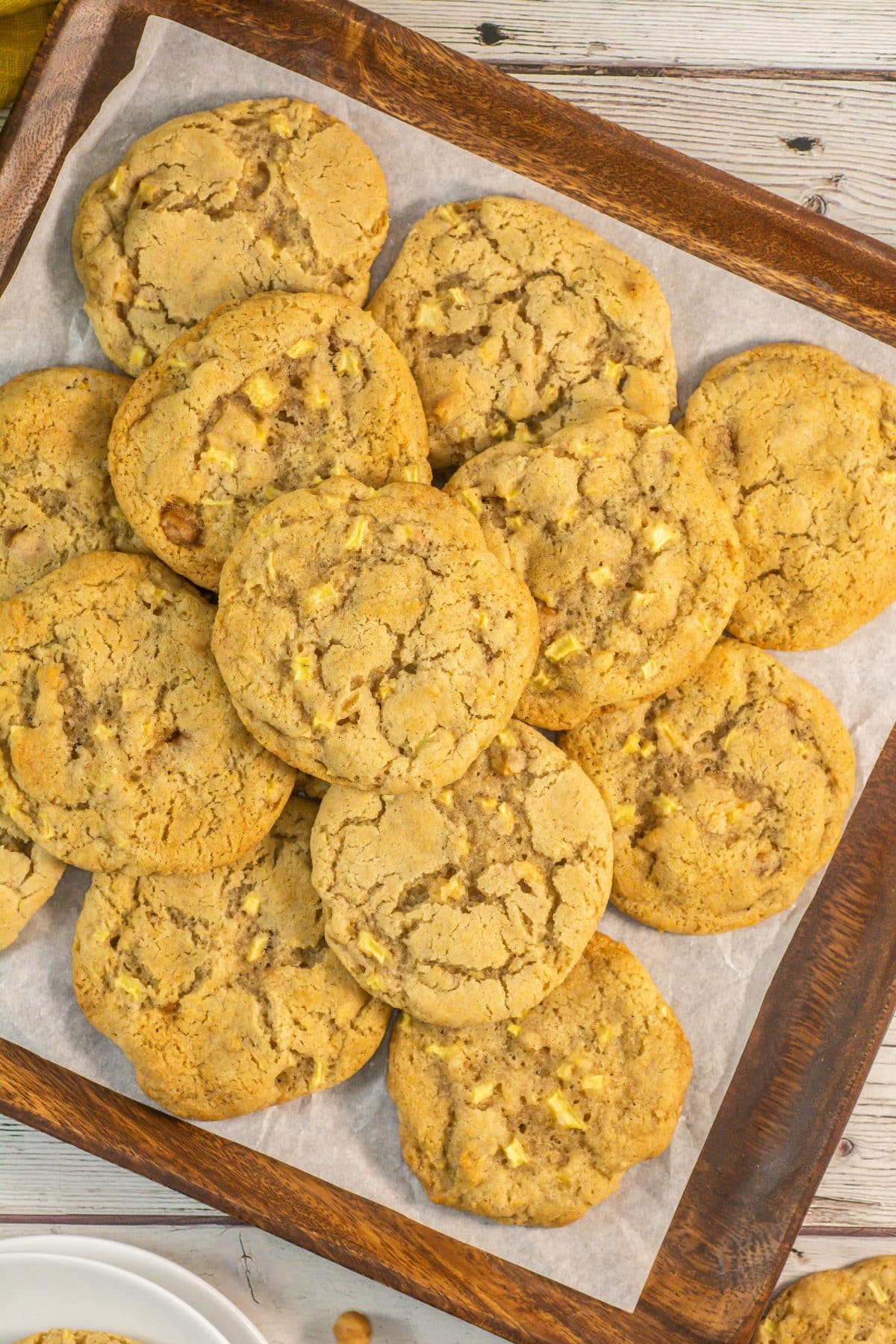 caramel apple cookies stacked on a parchment paper lined baking sheet
