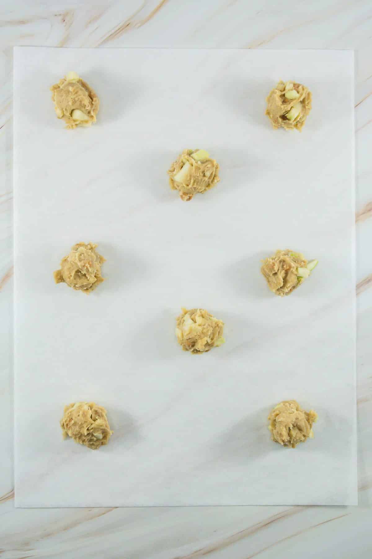 balls of caramel apple cookie dough arranged in rows on a sheet of white parchment paper