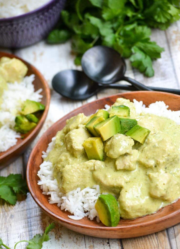 instant pot creamy avocado chicken over steamed white rice on a wooden plate
