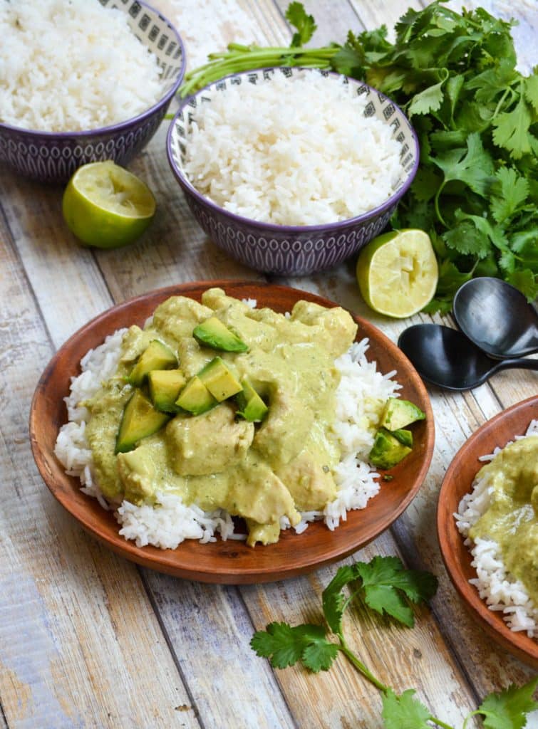 instant pot creamy avocado chicken over steamed white rice on a wooden plate