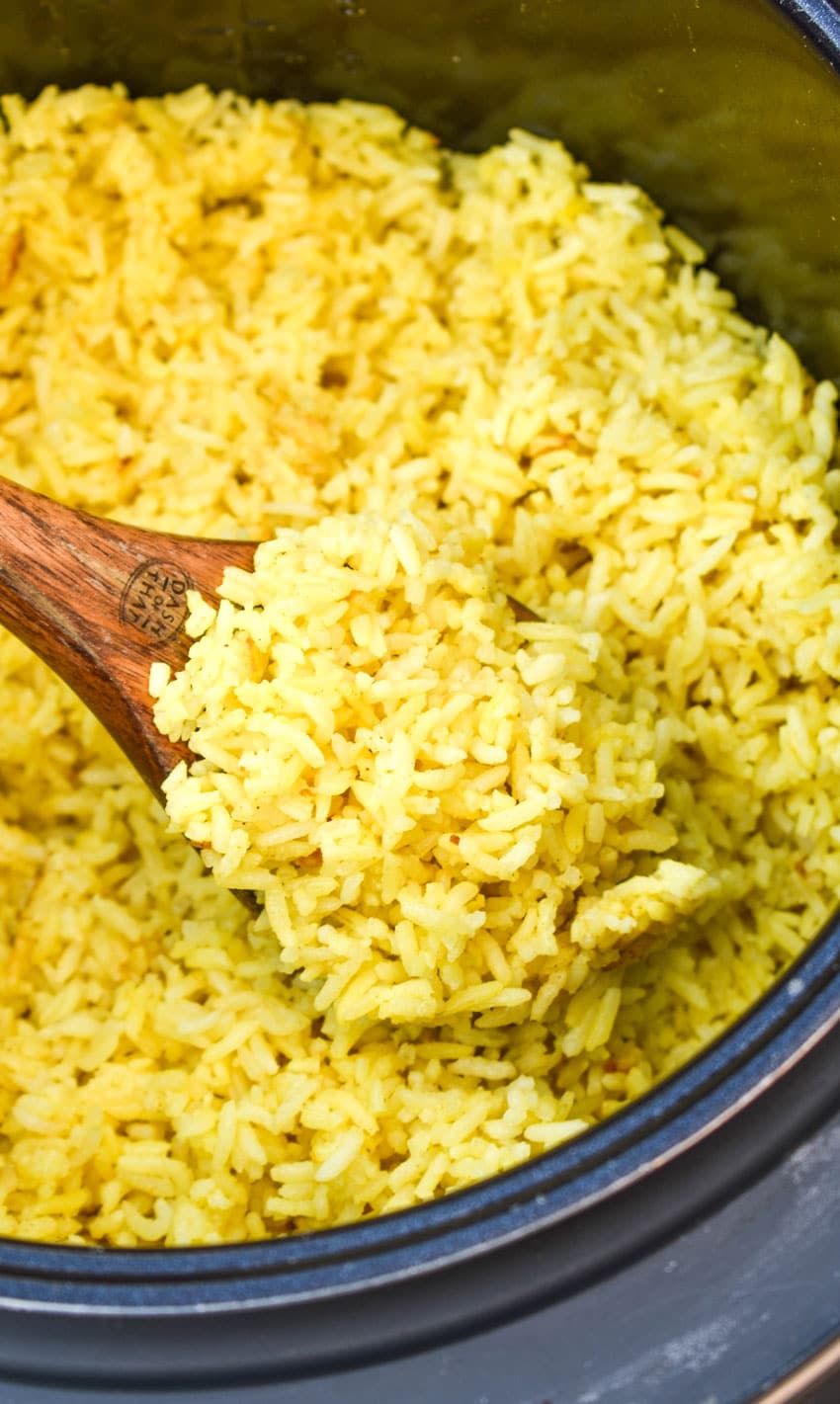 a wooden spoon scooping yellow rice out of an instant pot