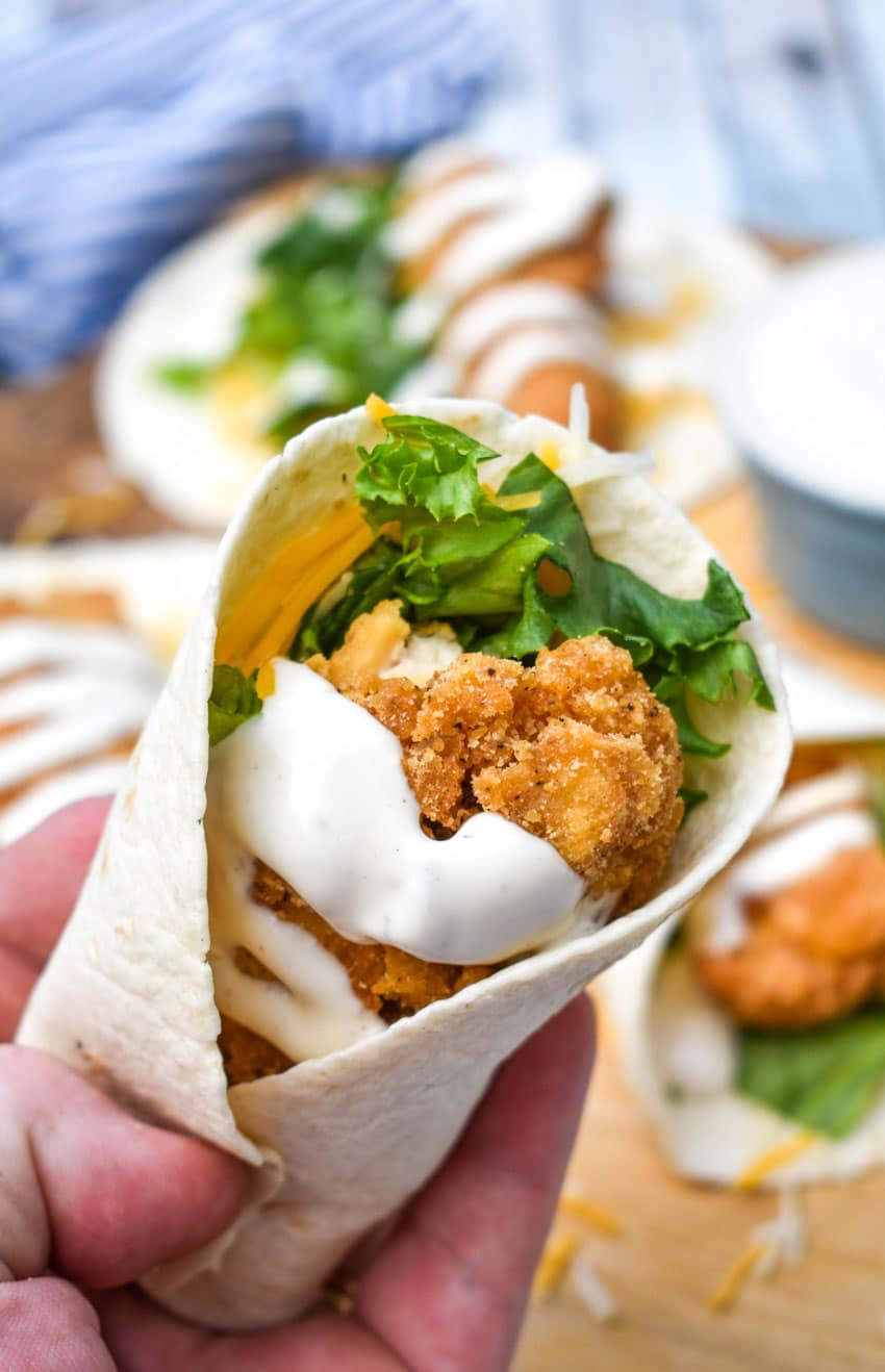 a hand holding up a copycat chicken snack wrap with ranch