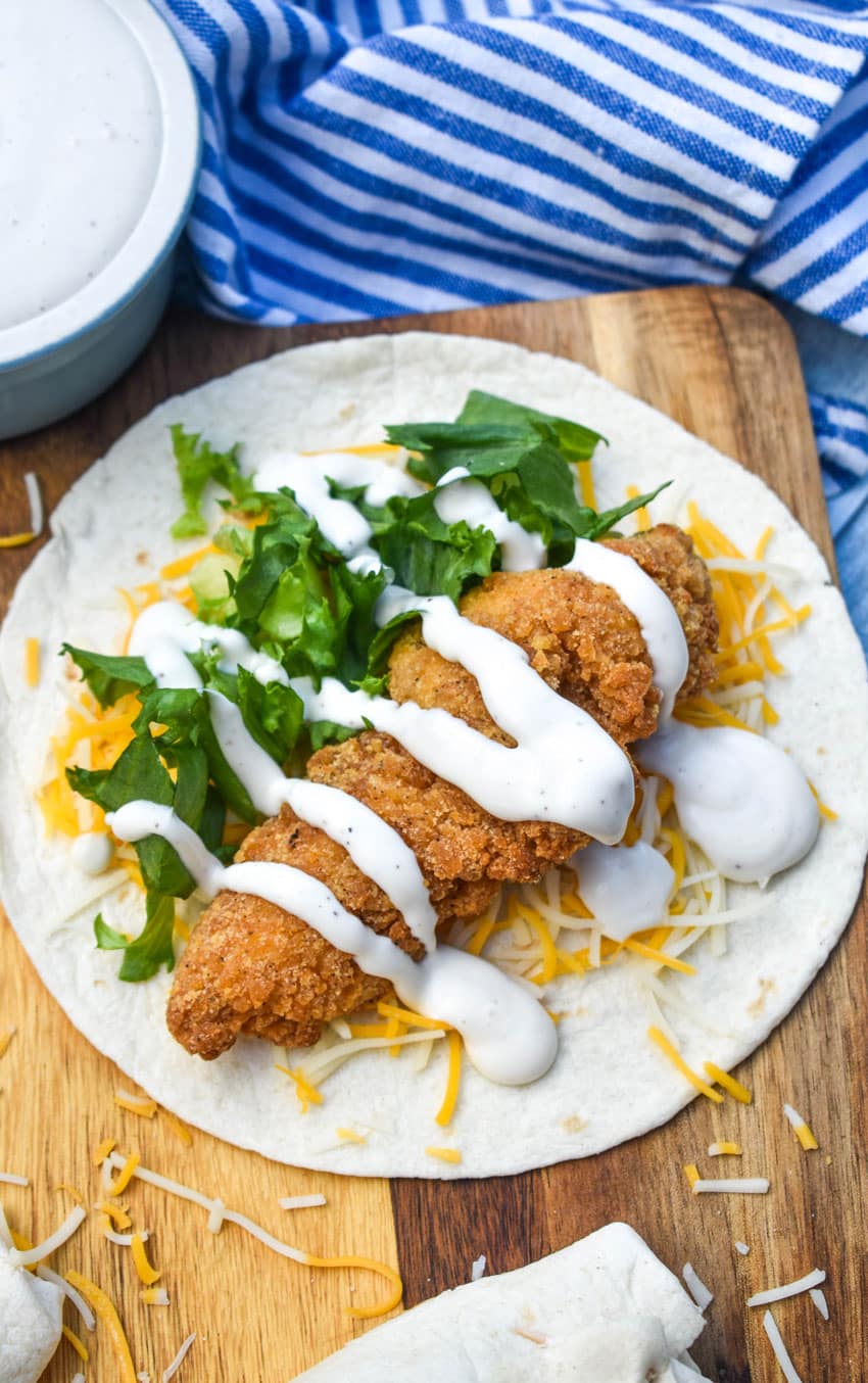 an open faced chicken snack wrap on a wooden cutting board