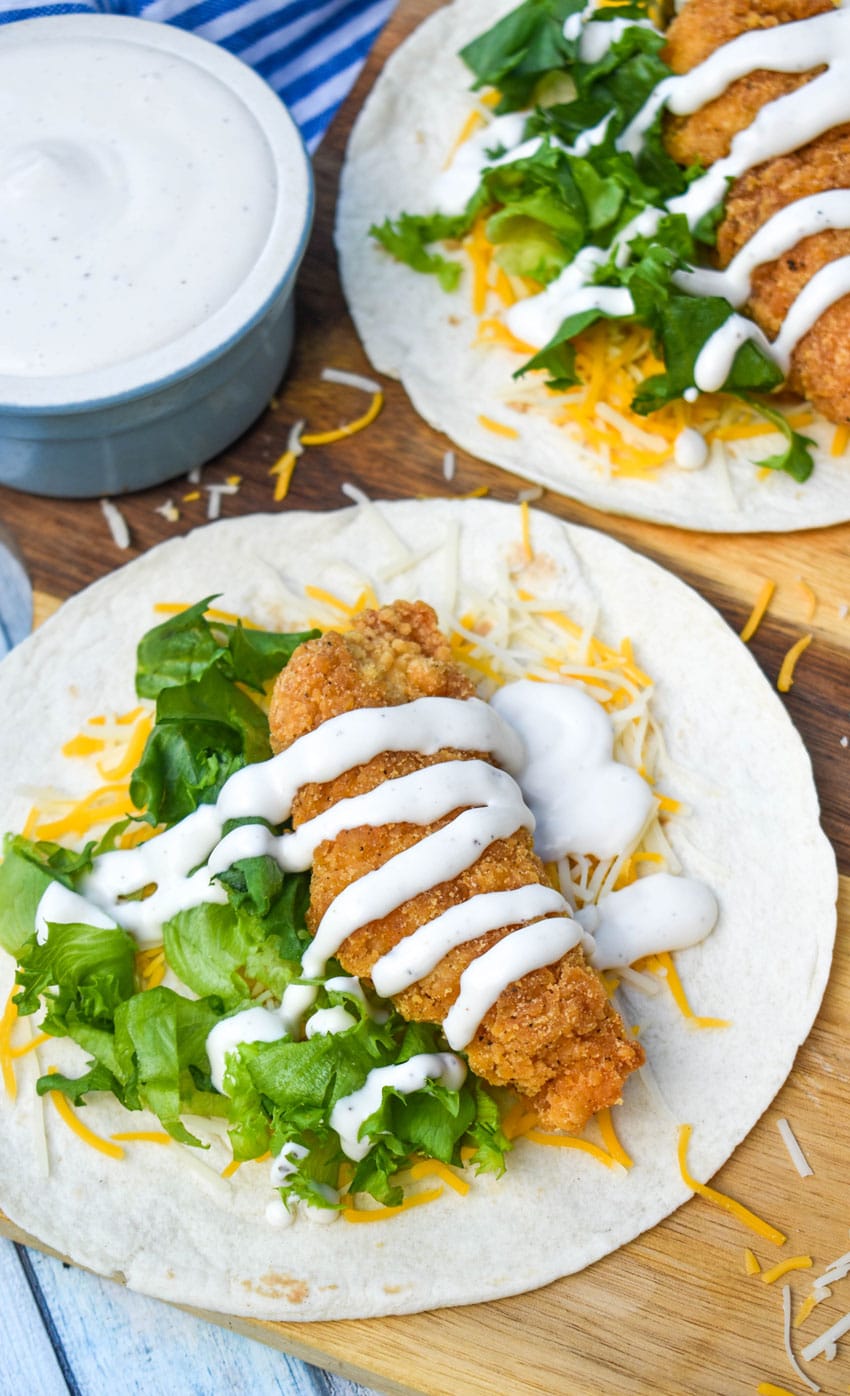 an open faced chicken snack wrap on a wooden cutting board