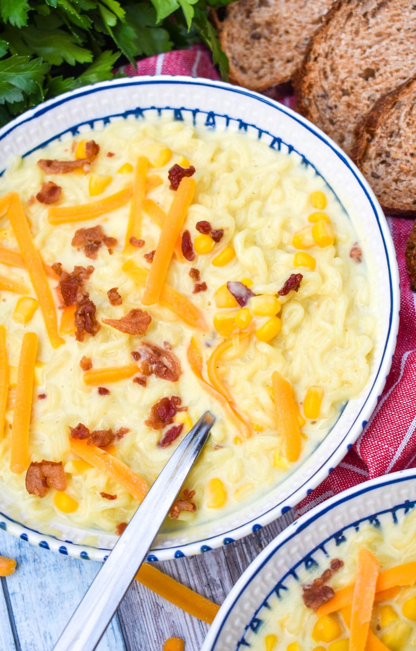 a silver spoon in a bowl of ramen noodle chowder