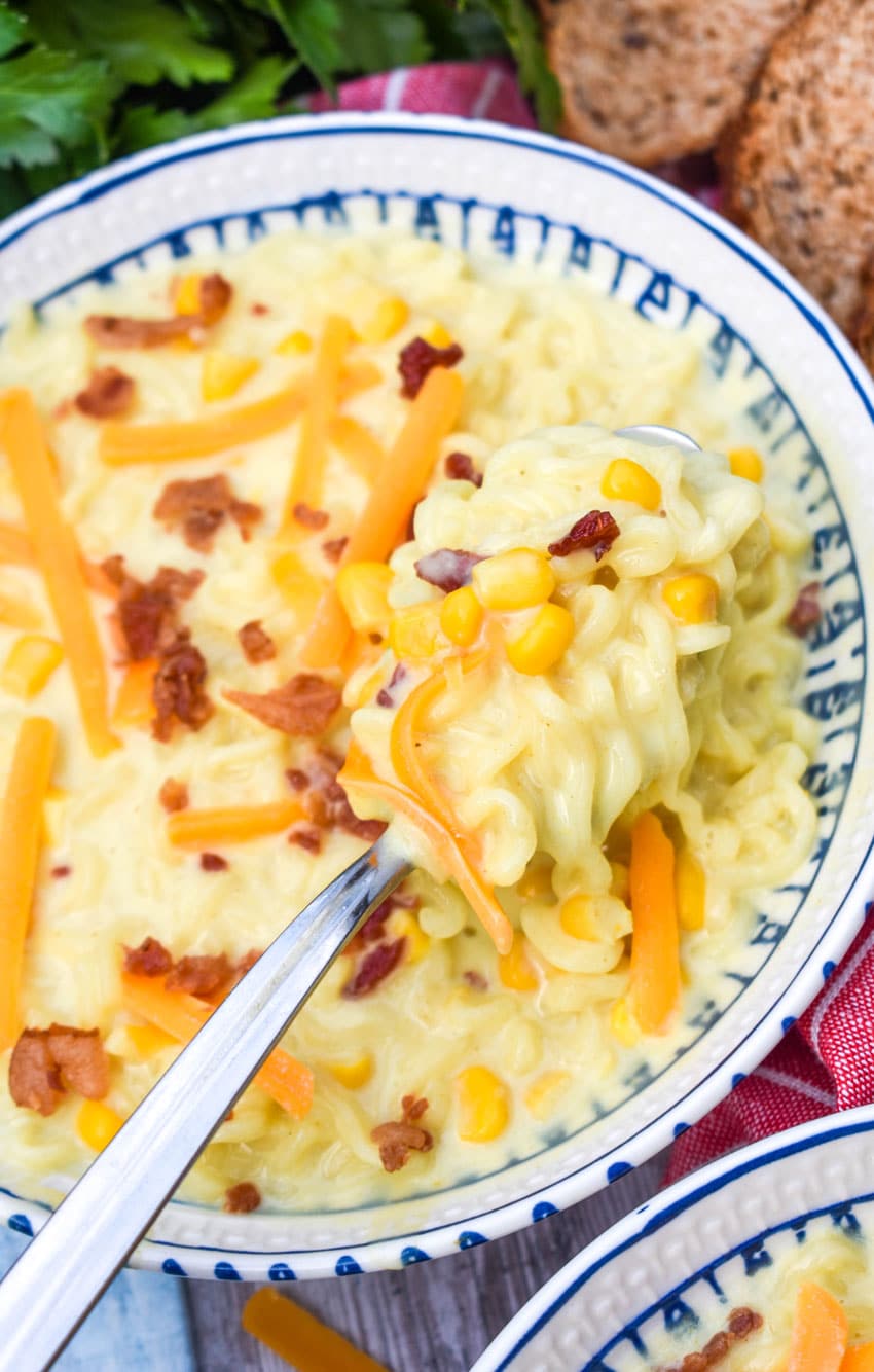 a silver spoon holding up a scoop of ramen noodle chowder