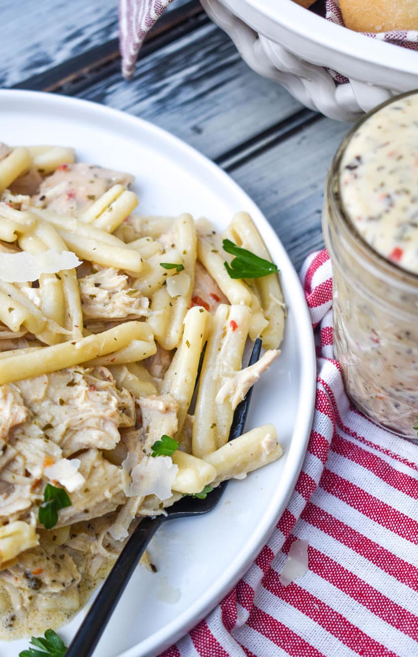 a black fork scooping garlic parmesan chicken and pasta off a white plate