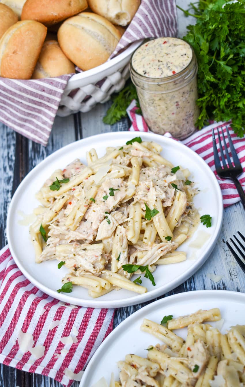 garlic parmesan chicken and pasta topped with fresh parsley leaves on a white plate