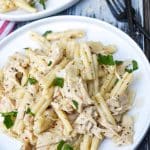 garlic parmesan chicken and pasta topped with fresh parsley leaves on a white plate