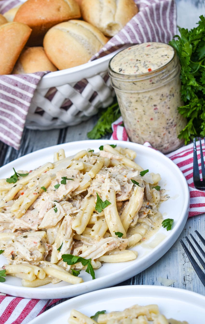 garlic parmesan chicken and pasta topped with fresh parsley leaves on a white plate