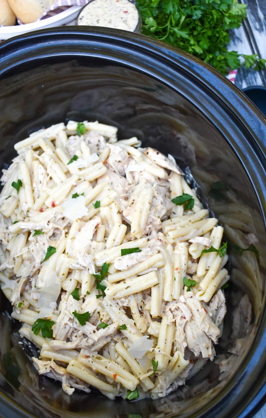 garlic parmesan chicken and pasta in the black bowl of a slow cooker