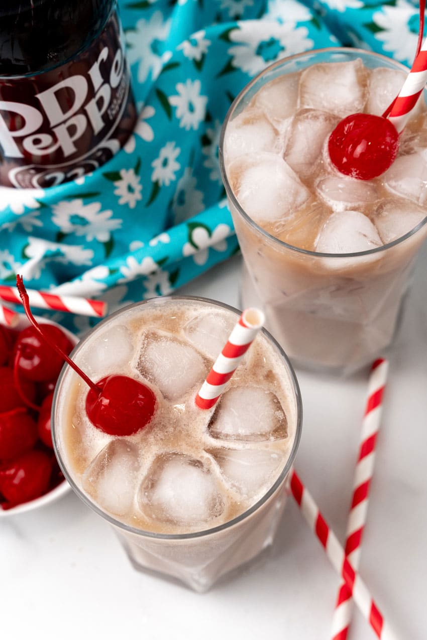dirty soda recipe in two glass jars with paper straws for garnish