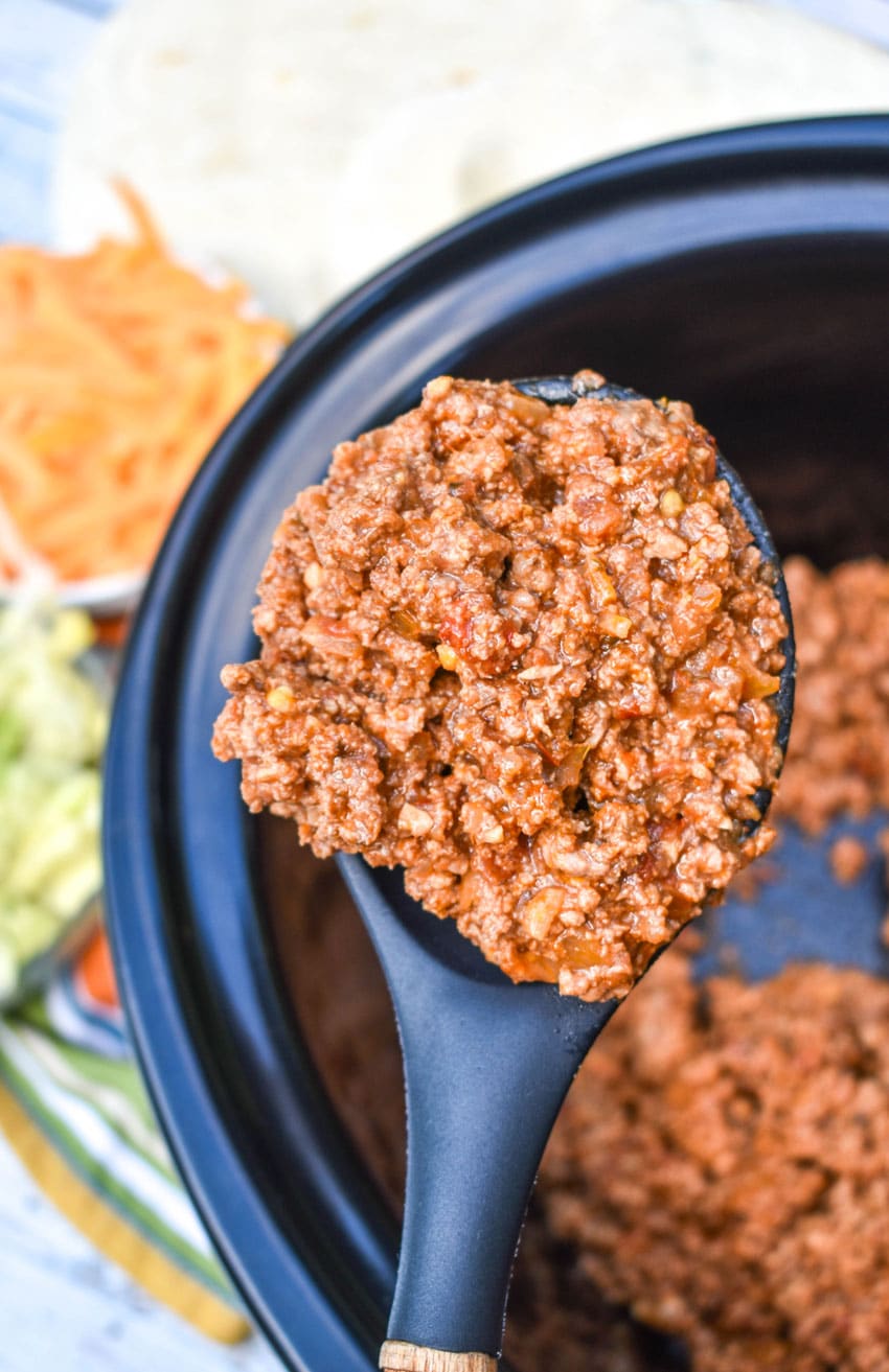 a spoon holding up a scoop of slow cooker taco meat