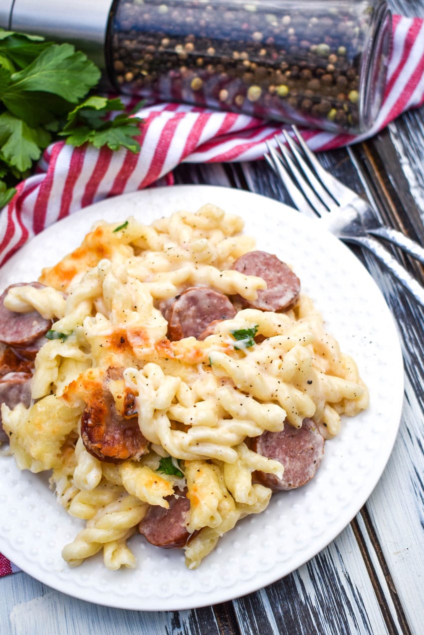 baked alfredo pasta with sausage on a white plate