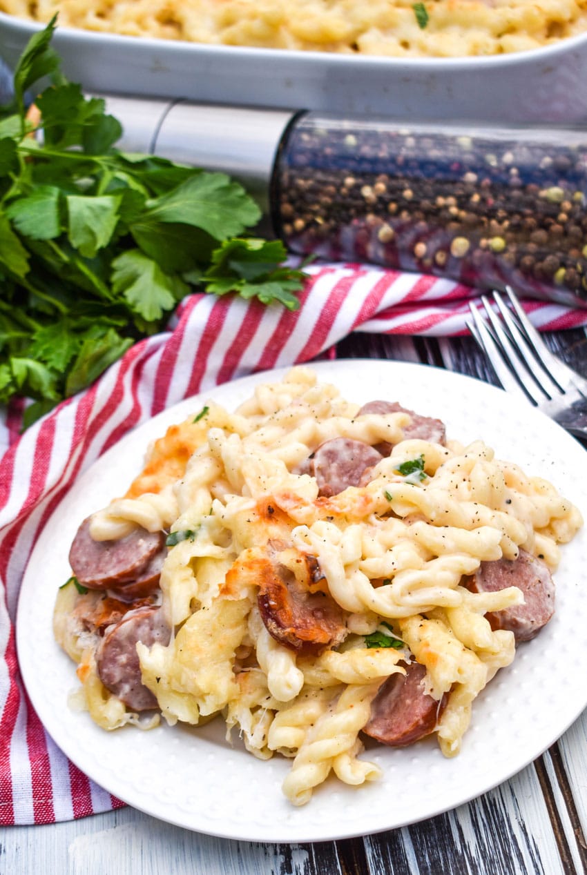 baked alfredo pasta with sausage on a white plate