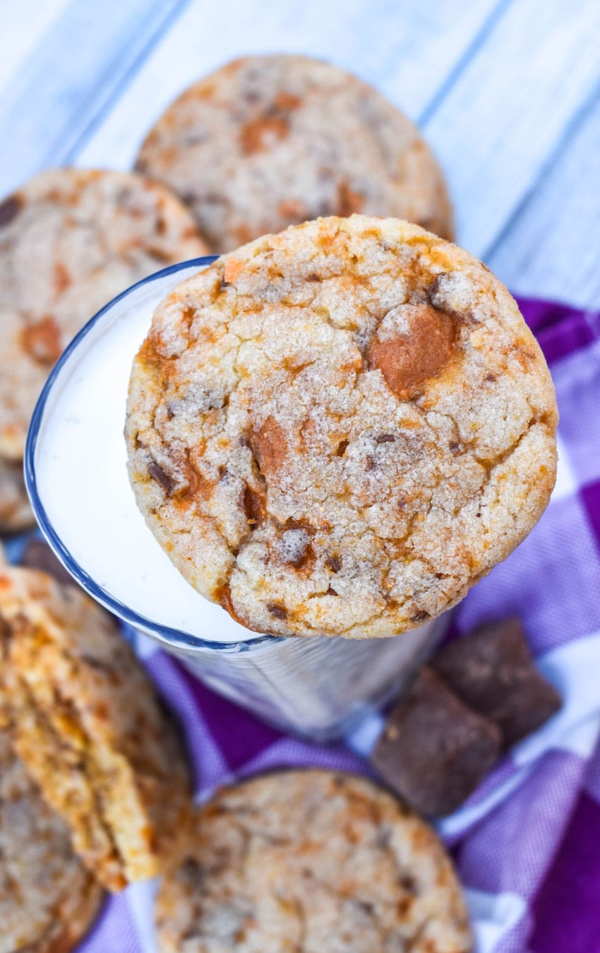 a butterfinger cookie resting on the rim of a glass of milk