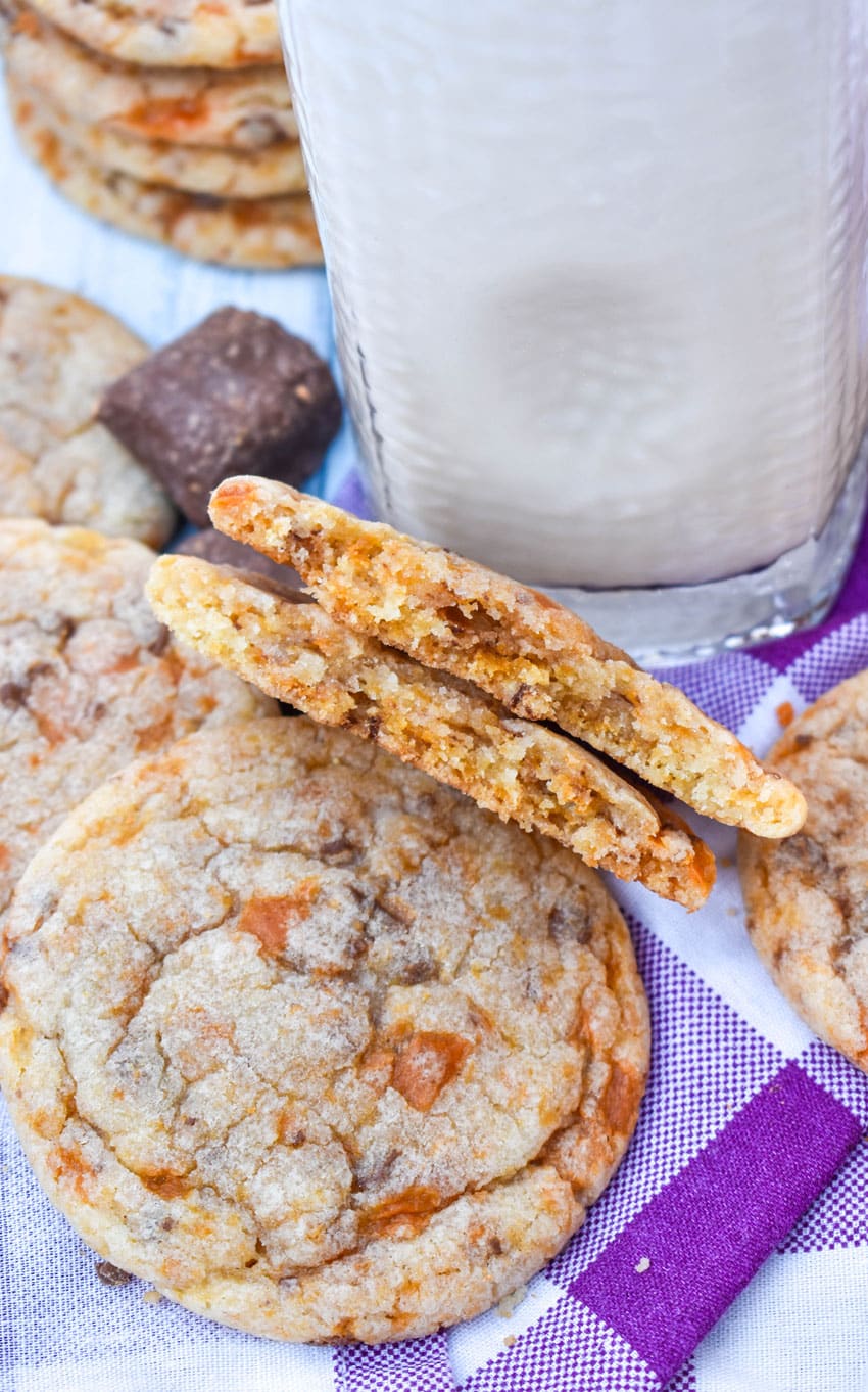 two halves of a butterfinger cookie propped up against a glass of milk to show to reveal the chewy inside
