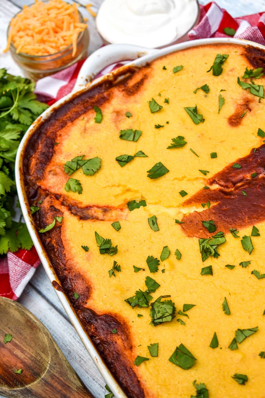 chili cornbread casserole topped with fresh herbs in a white baking dish