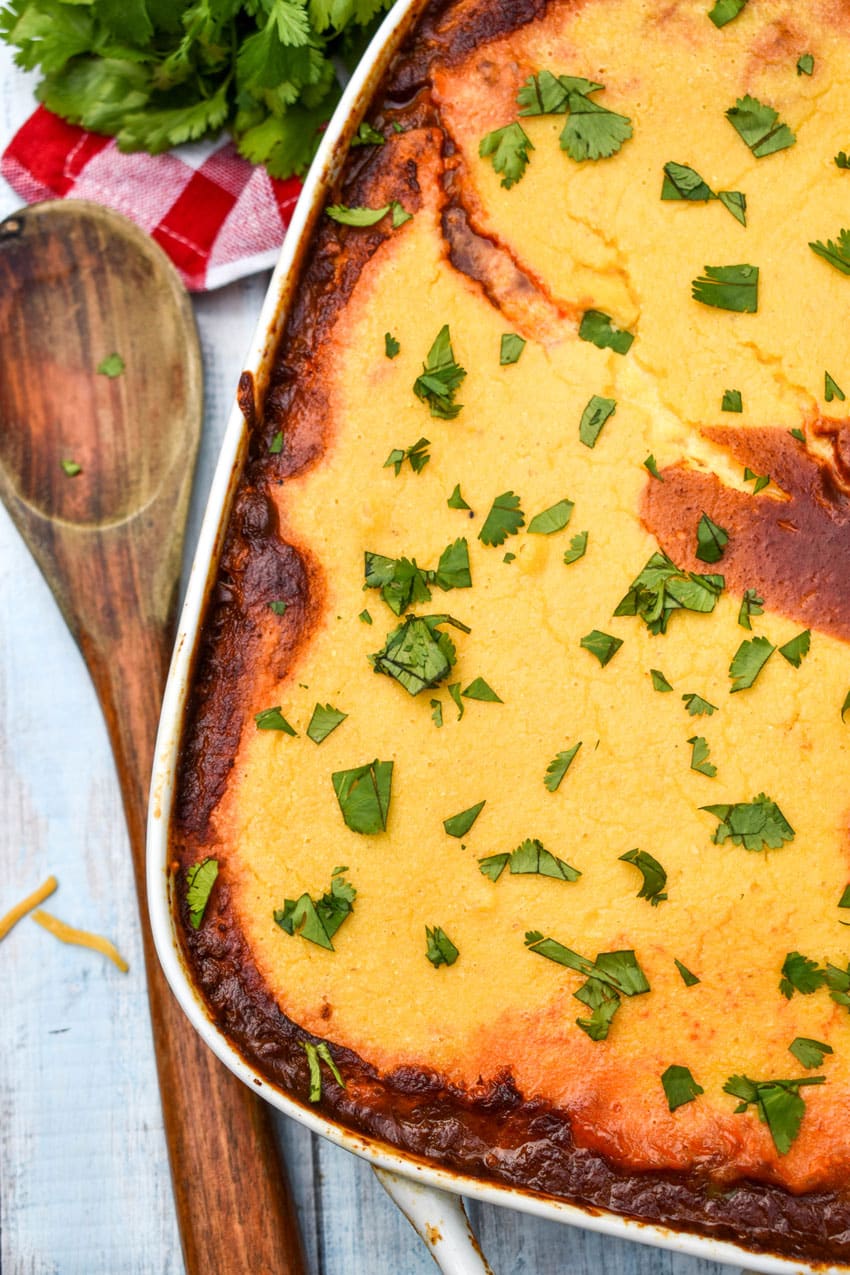 chili cornbread casserole topped with fresh herbs in a white baking dish
