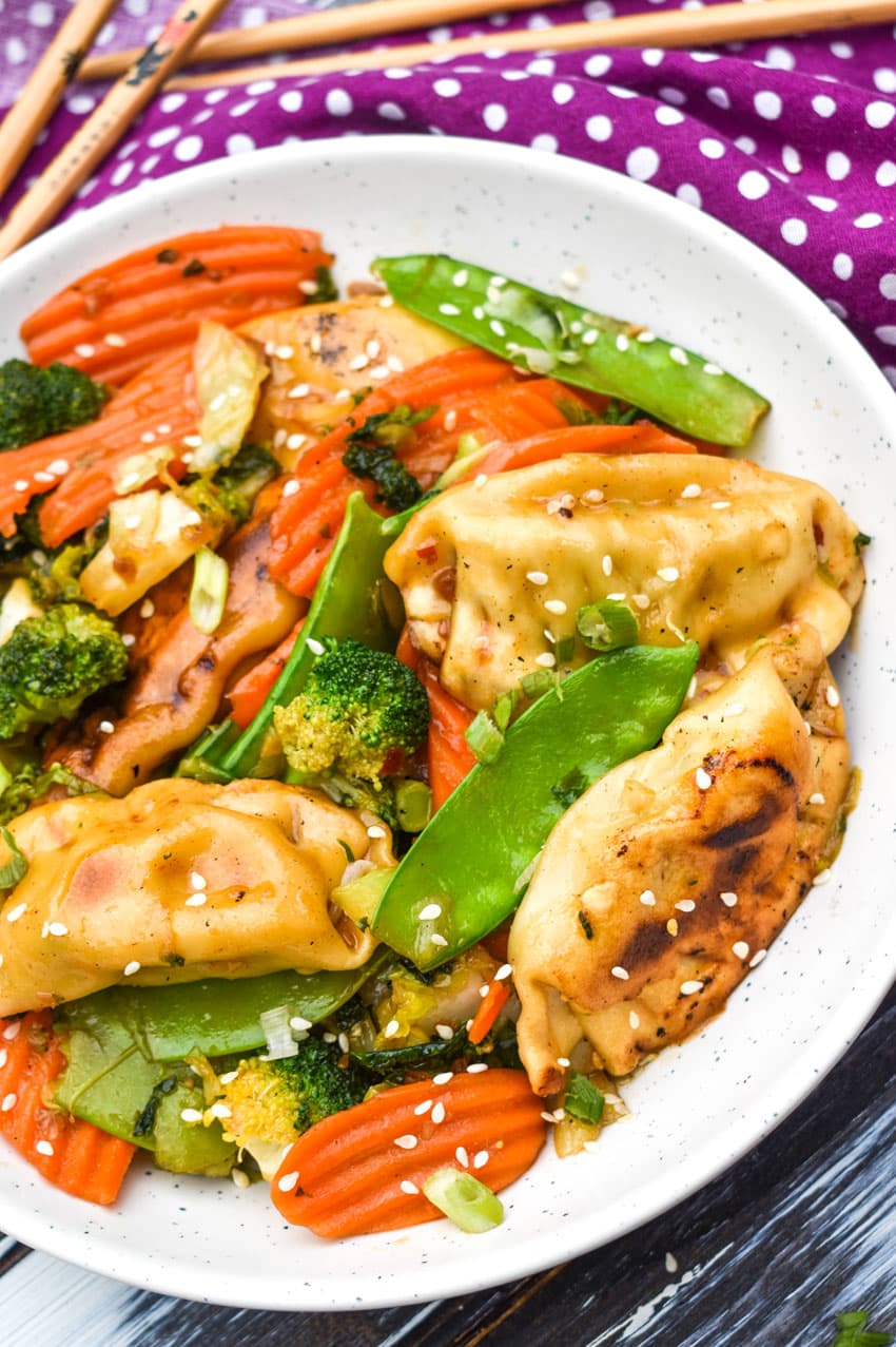 easy potsticker stir fry in a white bowl with wooden chop sticks on the side