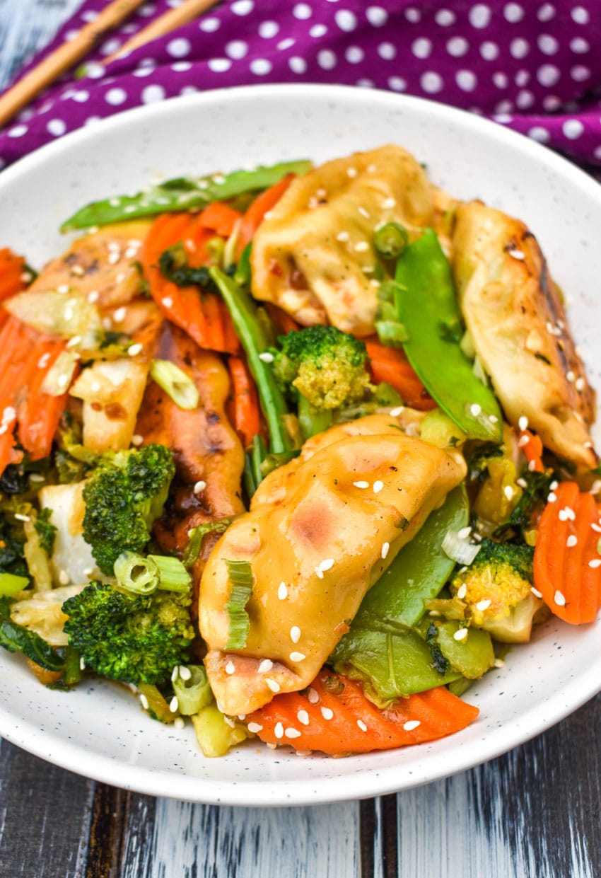 easy potsticker stir fry in a white bowl with wooden chop sticks on the side