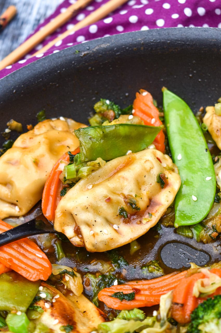 a black spoon scooping easy potsticker stir fry out of a black skillet