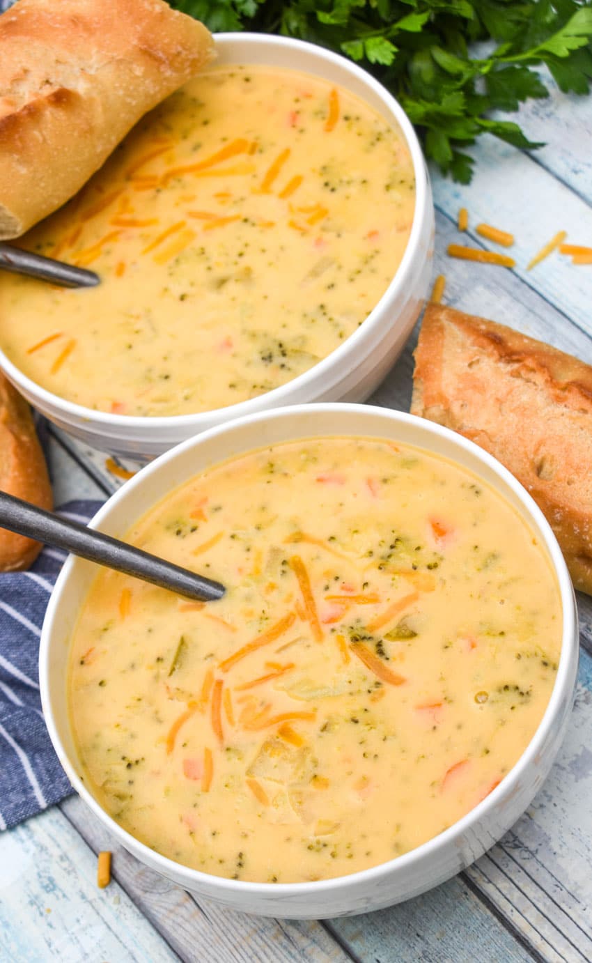instant pot broccoli cheddar soup topped with shredded cheddar cheese in two white bowls