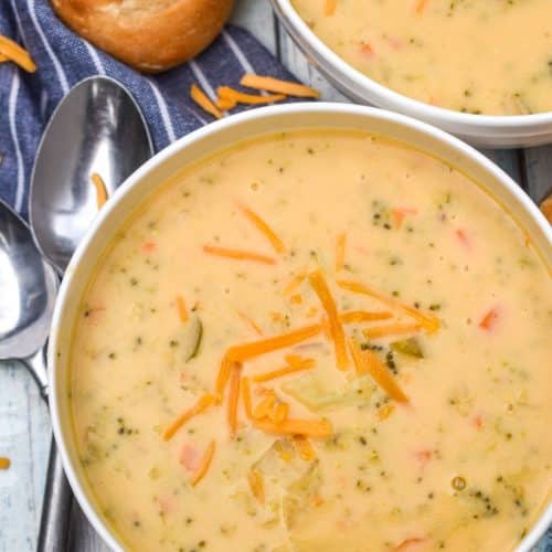 instant pot broccoli cheddar soup topped with shredded cheddar cheese in two white bowls