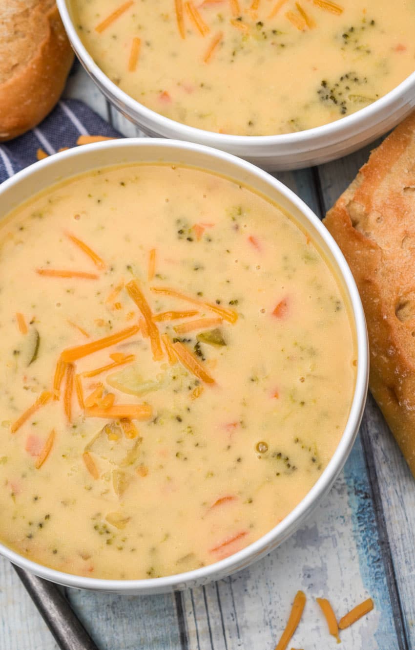 instant pot broccoli cheddar soup topped with shredded cheddar cheese in two white bowls
