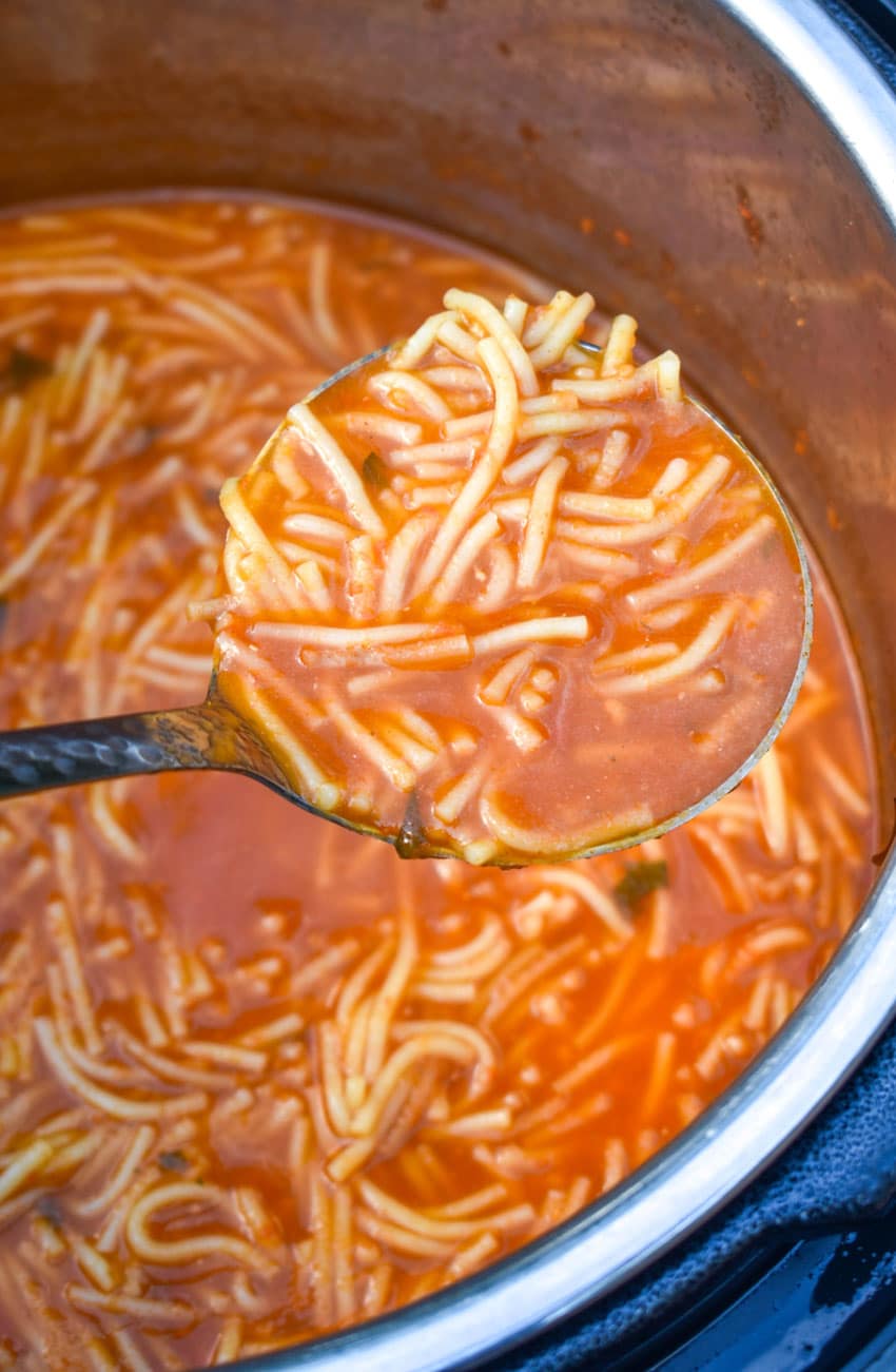 a silver ladle scooping sopa de fideo out of an instant pot