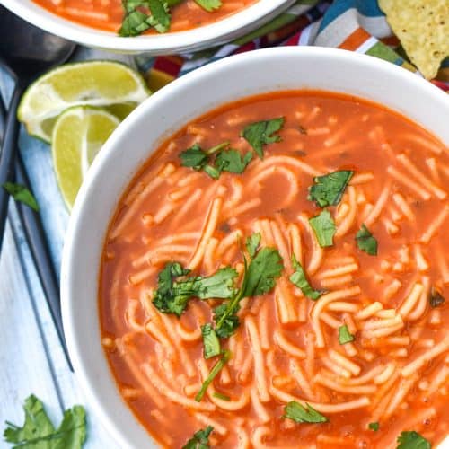 instant pot sopa de fideo topped with fresh cilantro leaves in two white soup bowls