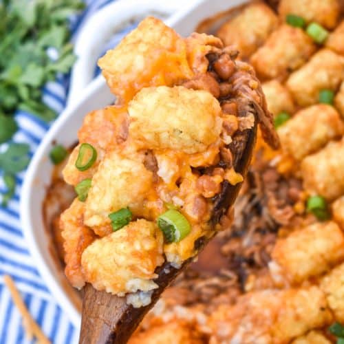 a wooden spoon holding up a scoop of pulled pork tater tot casserole