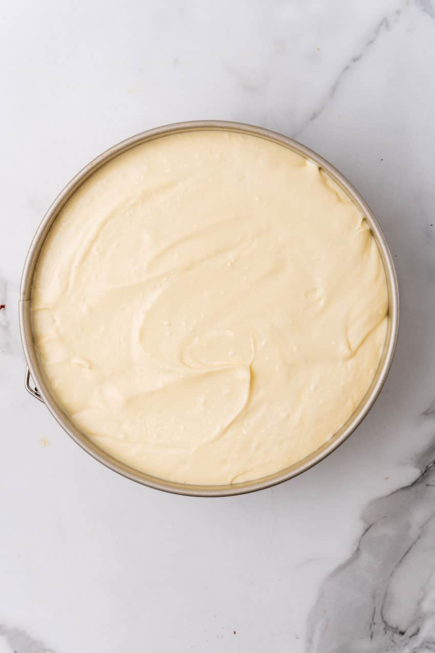 an unbaked brownie bottom cheesecake in a metal springform pan