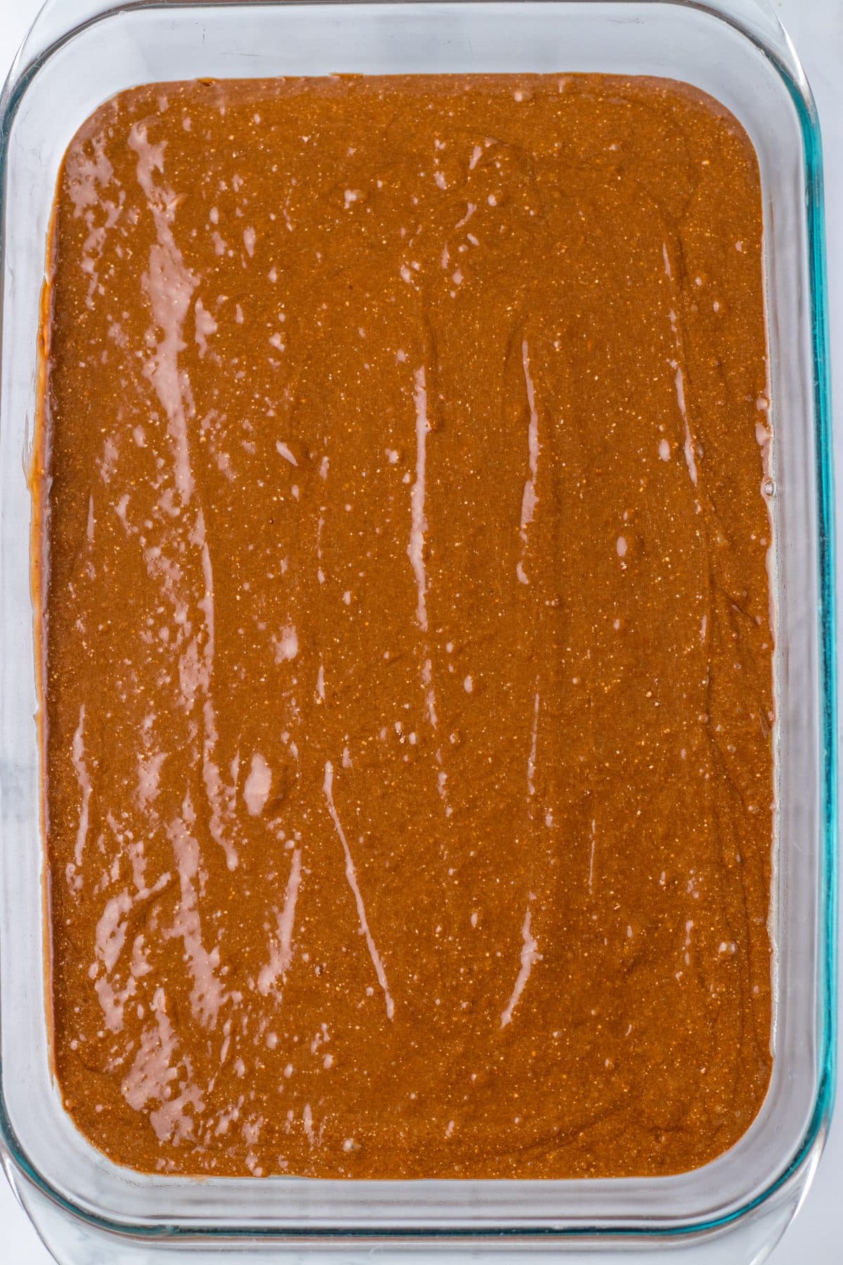 chocolate cake batter spread out in a 9x13 inch glass baking dish