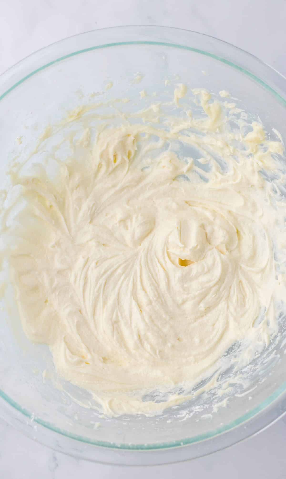 homemade whipped cream frosting in a glass mixing bowl