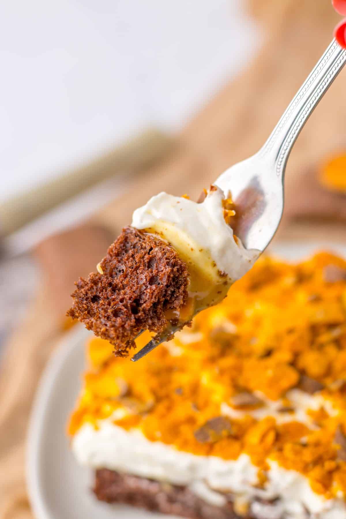 a silver fork holding up a scoop of butterfinger poke cake