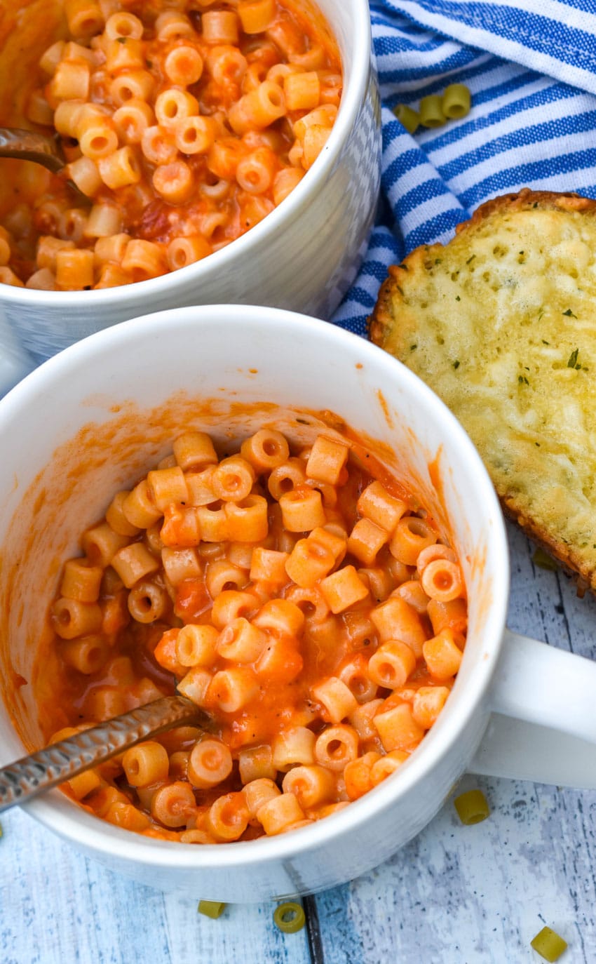 a silver spoon scooping homemade spaghettio's out of a large white microwave mug