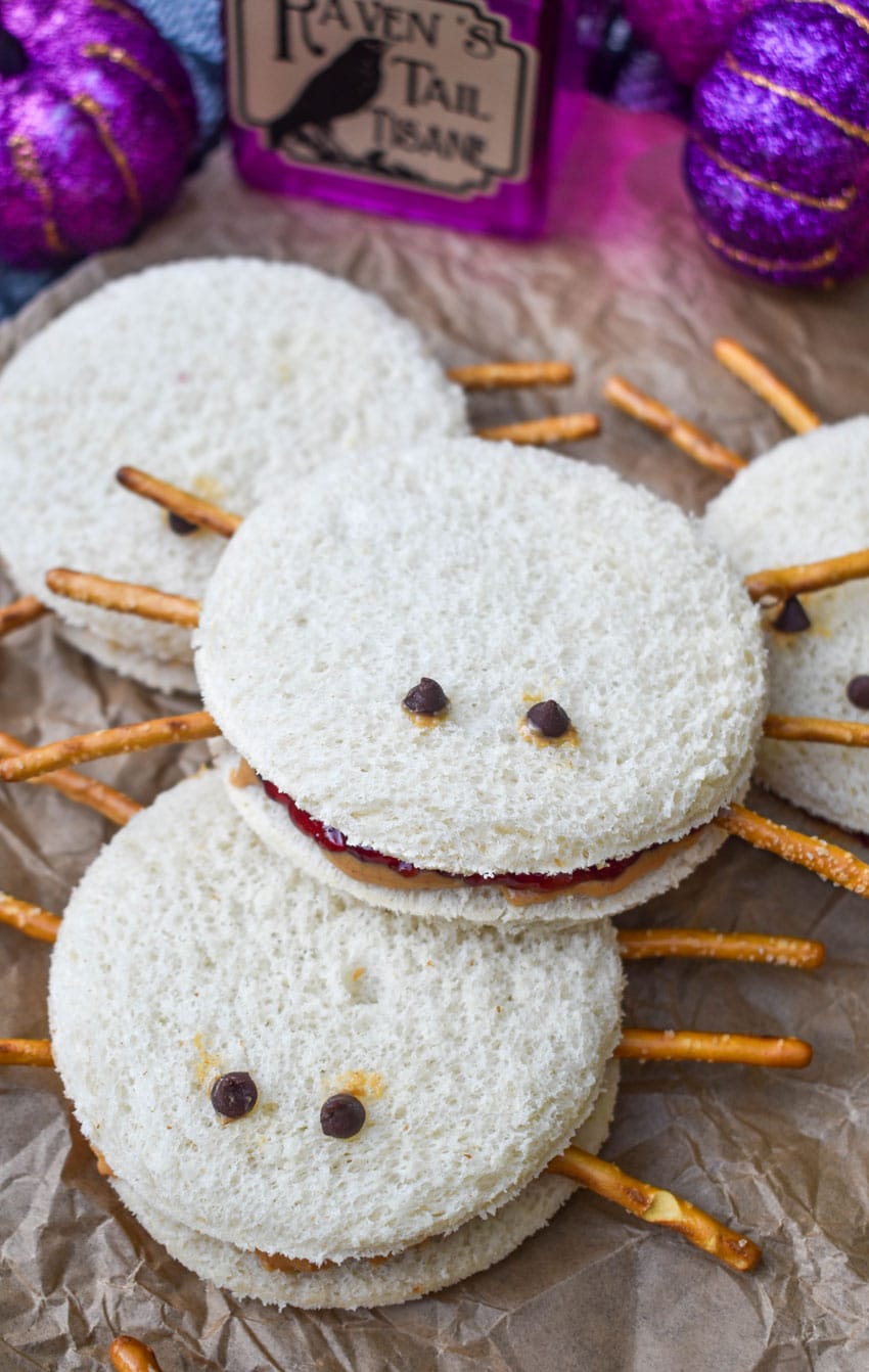 a pile of spider peanut butter and jelly sandwiches on a crinkled sheet of brown parchment paper
