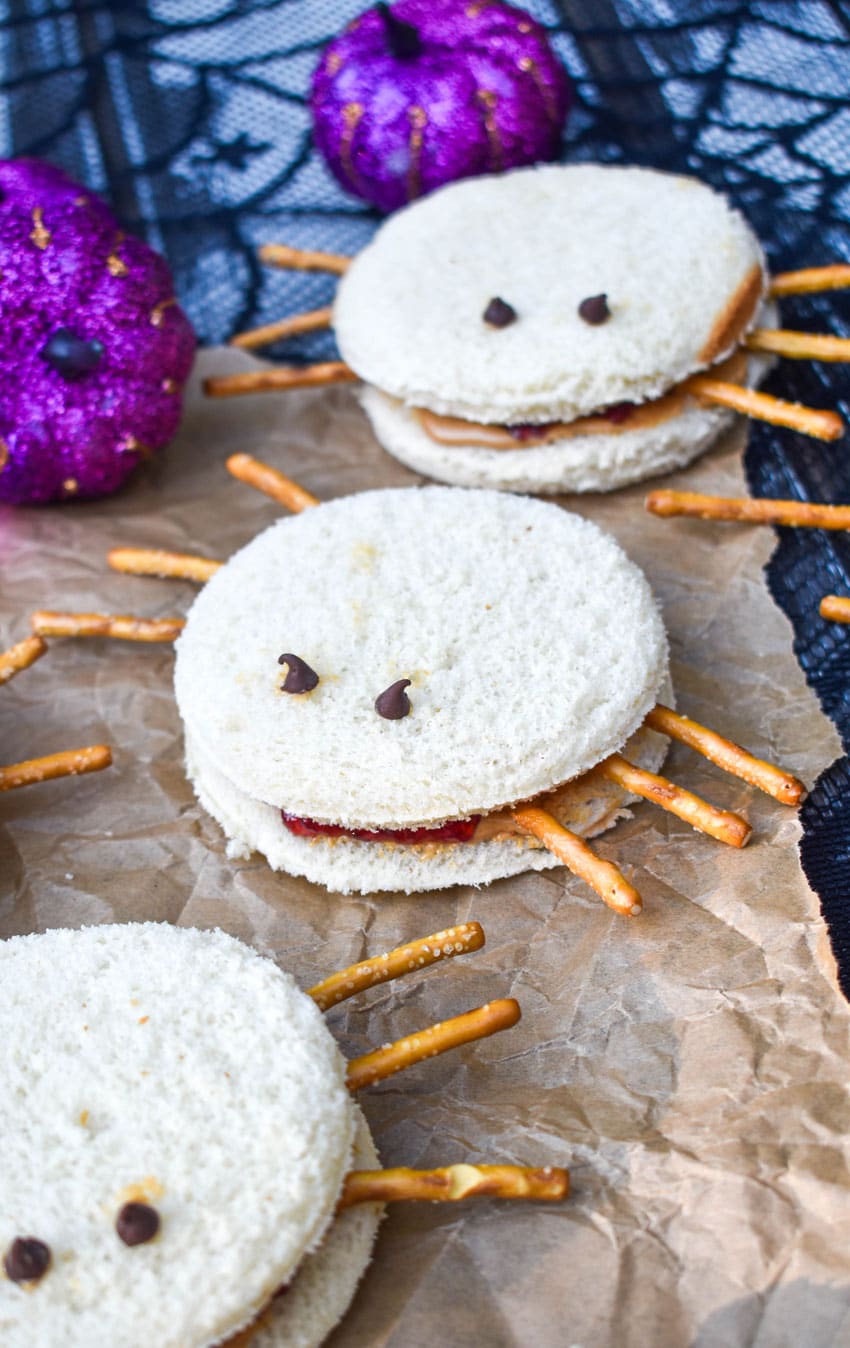 spider peanut butter and jelly sandwiches on a crinkled sheet of brown parchment paper