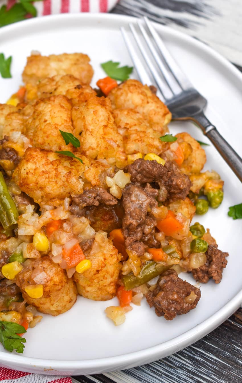 shepherds pie tater tot casserole on a white dinner plate with a silver fork resting on the side