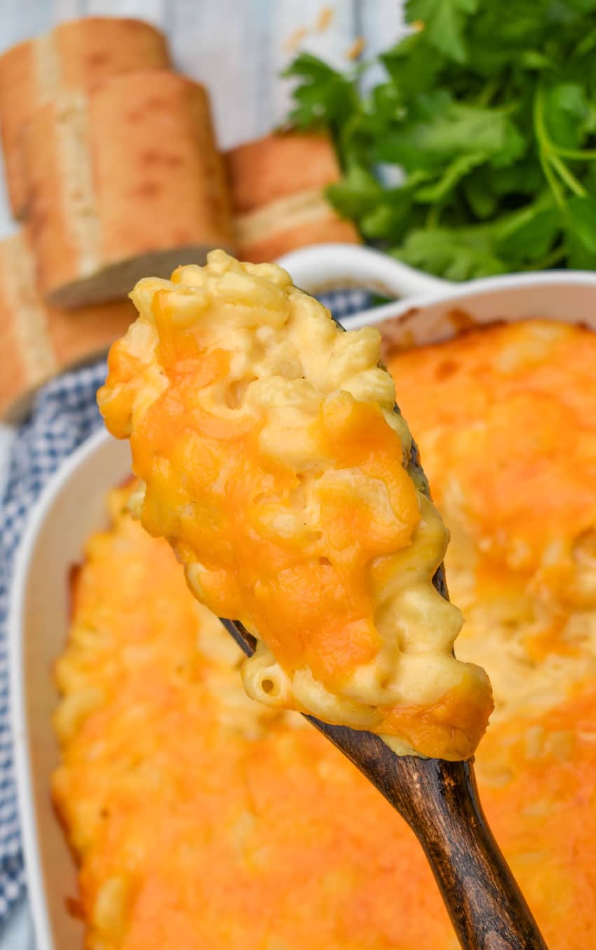 a wooden spoon holding up a scoop of the creamiest homemade macaroni and cheese