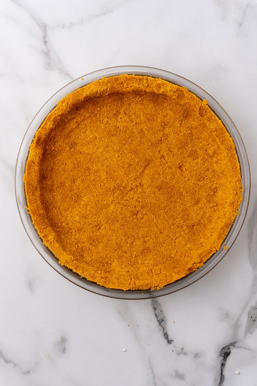 a baked homemade graham cracker crust on a marble counter top
