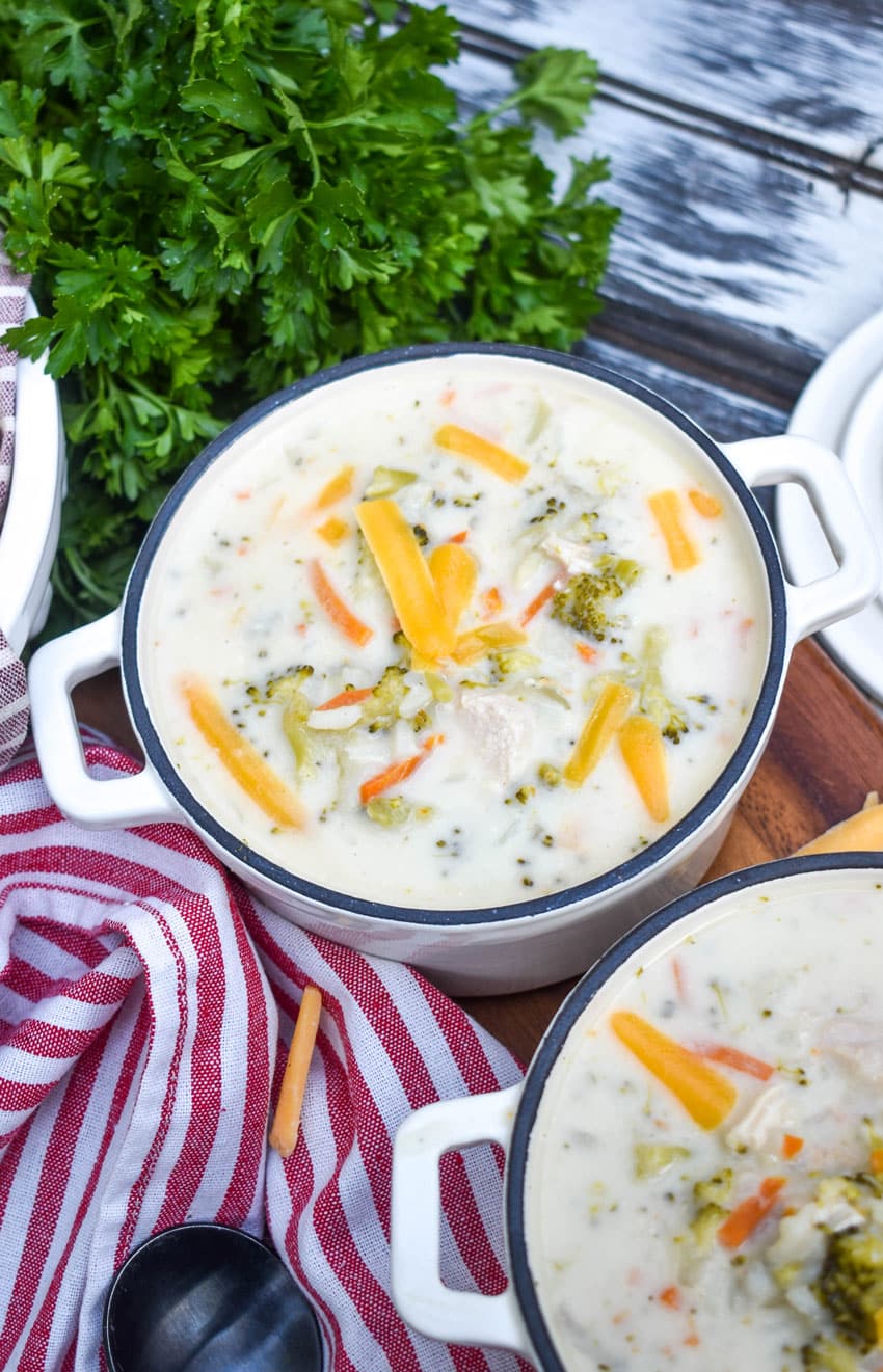 A BOWL OF CREAMY CHICKEN AND RICE A RONI SOUP ON A WOODEN CUTTING BOARD