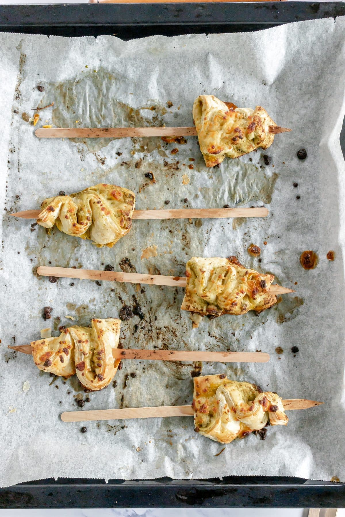 baked pesto puff pastry christmas trees on a parchment paper lined baking pan