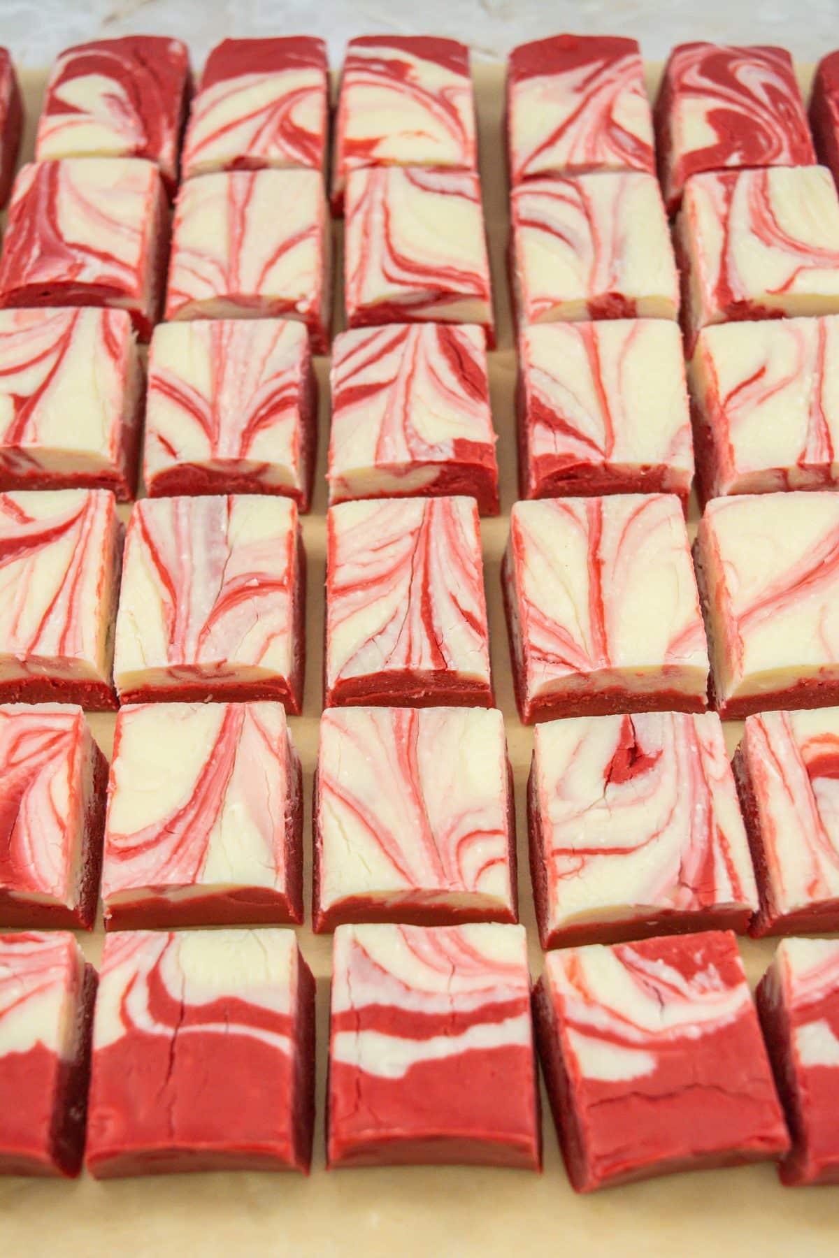 sliced squares of red velvet fudge on a wooden cutting board