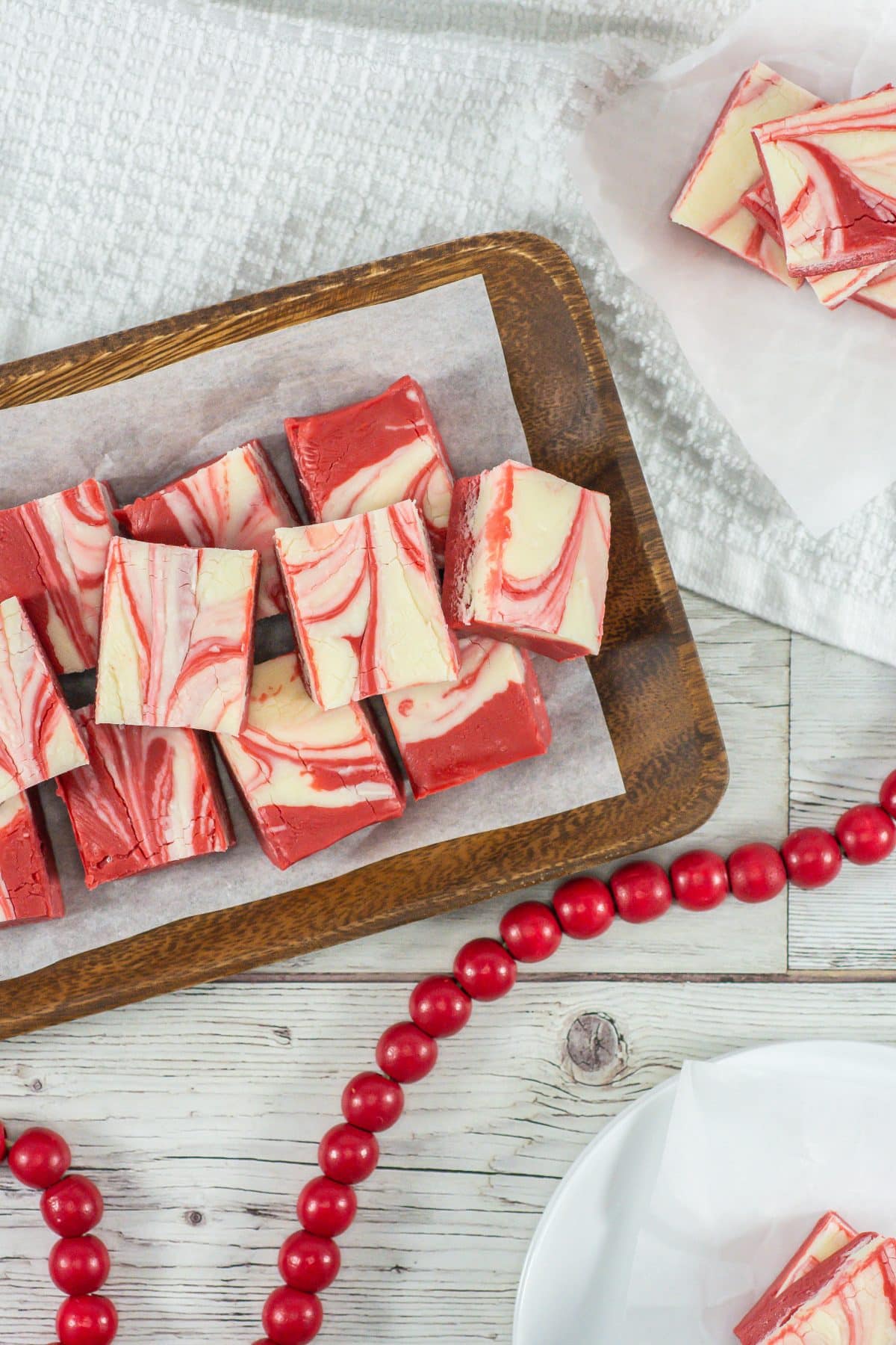squares of red velvet fudge stacked on a parchment paper lined wooden serving tray