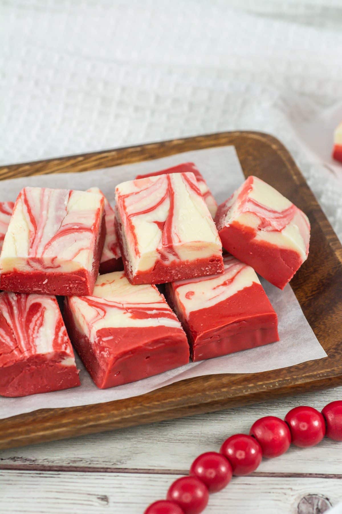 squares of red velvet fudge stacked on a parchment paper lined wooden serving tray