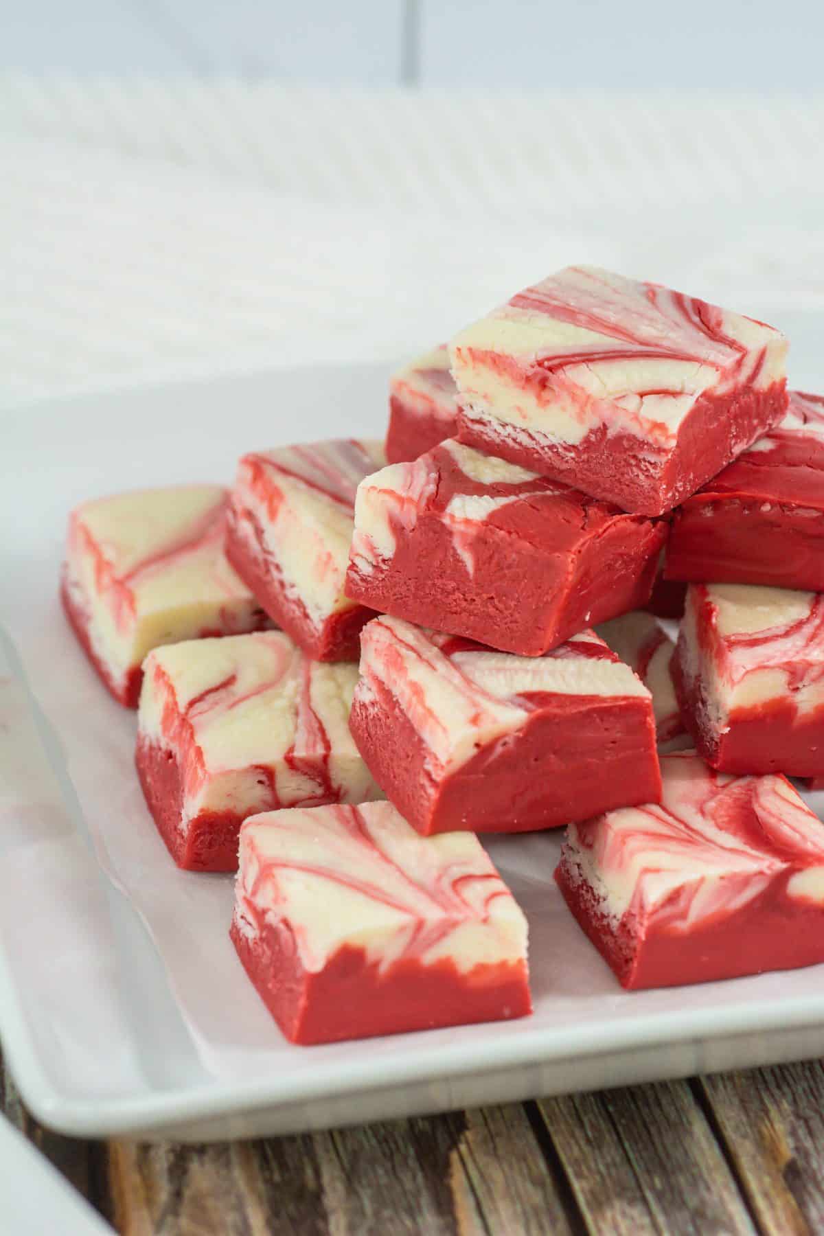 squares of red velvet fudge stacked on a white square serving plate