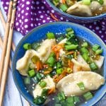 potsticker soup in a blue bowl with wooden chop sticks on the side